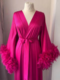 A bright pink satin robe with long sleeves and feather details, displayed on a mannequin.