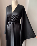 a woman is holding a black robe on a mannequin