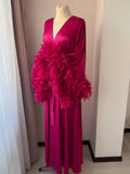 A mannequin wearing a long, pink dress with a large, fluffy feather accessory.