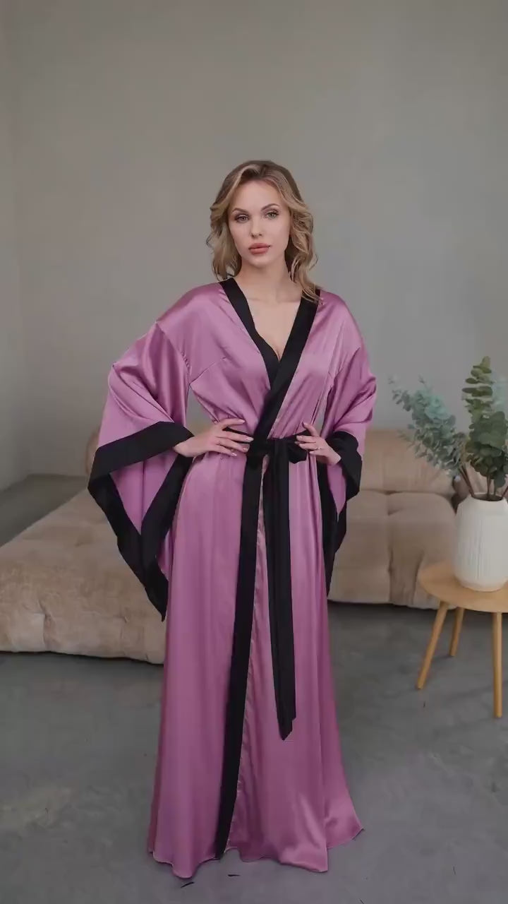 Video of flowing purple satin floor length robe with black trim on model