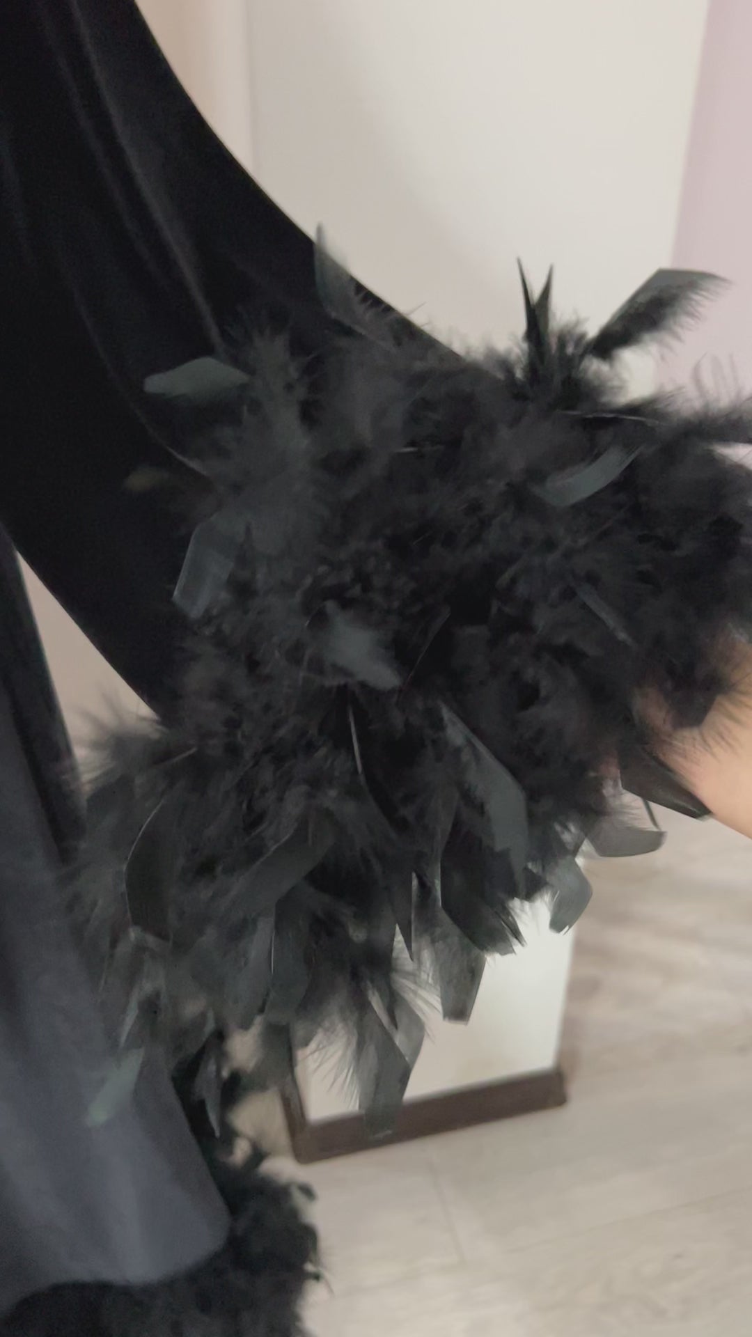 Video showcasing black velvet robe with decorative feather trim