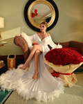 the bride in white with feathers sits on the couch