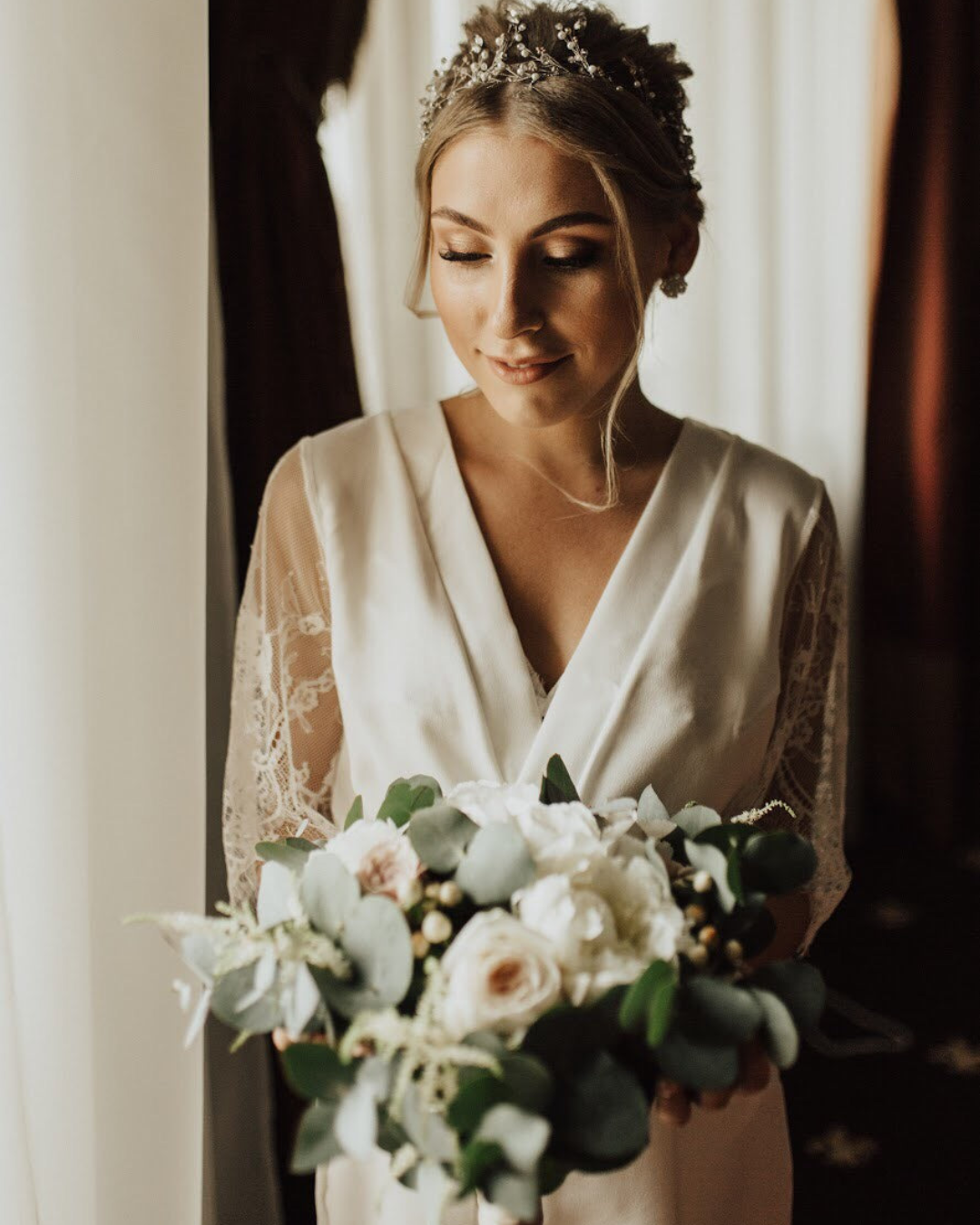 a woman in a white bridal robe holding a bouquet of flowers