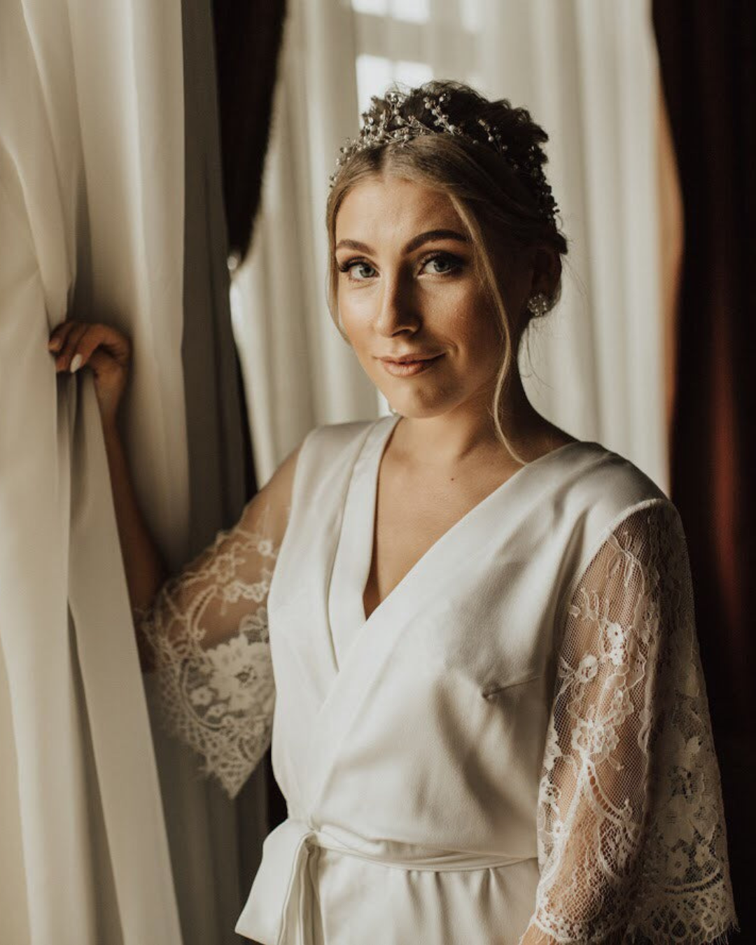 a bride standing next to a window wearing a white dress