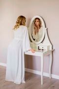 the bride in a robe in front of a mirror